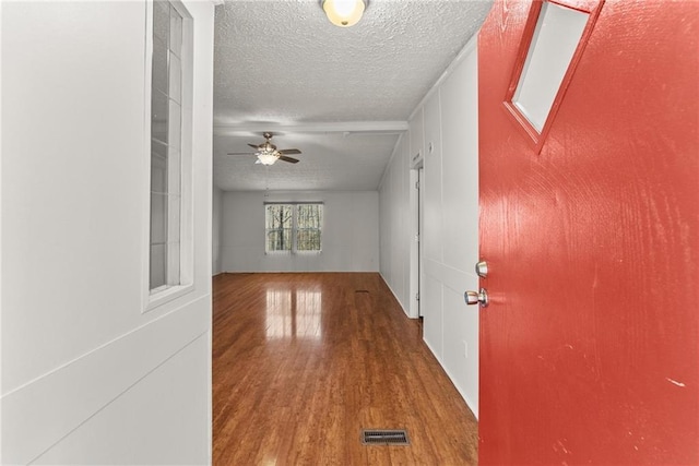 corridor with wood-type flooring and a textured ceiling