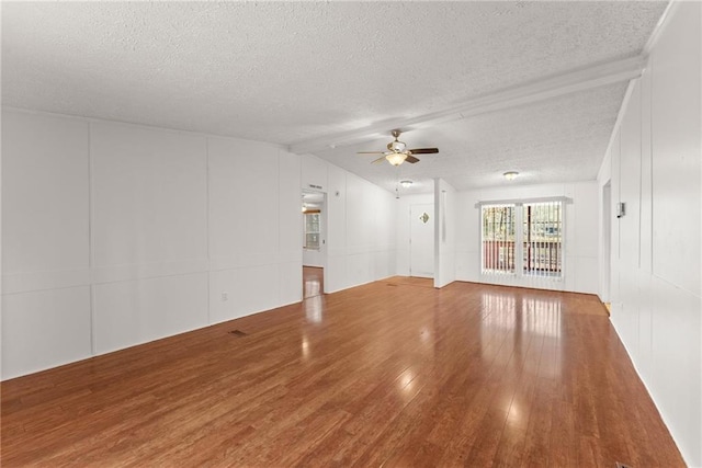 unfurnished living room with vaulted ceiling with beams, hardwood / wood-style flooring, a textured ceiling, and ceiling fan