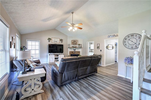 10 Alexandria Ln, Dallas, GA 30132 - living room featuring wood finished floors, ceiling fan, vaulted ceiling, a fireplace, and a textured ceiling