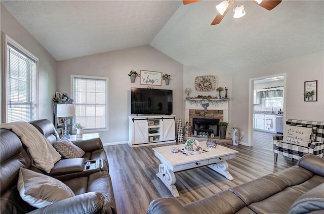 10 Alexandria Ln, Dallas, GA 30132 - living room with wood finished floors, ceiling fan, vaulted ceiling, a fireplace, and a textured ceiling