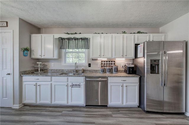 10 Alexandria Ln, Dallas, GA 30132 - kitchen featuring appliances with stainless steel finishes, a textured ceiling, white cabinets, light wood finished floors, and light stone counters