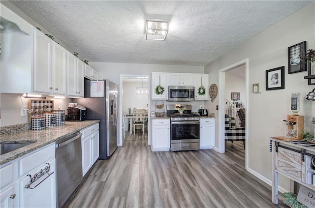 10 Alexandria Ln, Dallas, GA 30132 - kitchen with stainless steel appliances, light wood-style floors, white cabinetry, a textured ceiling, and light stone counters