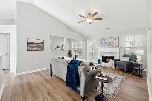 living room featuring ceiling fan, light hardwood / wood-style floors, lofted ceiling, and a fireplace