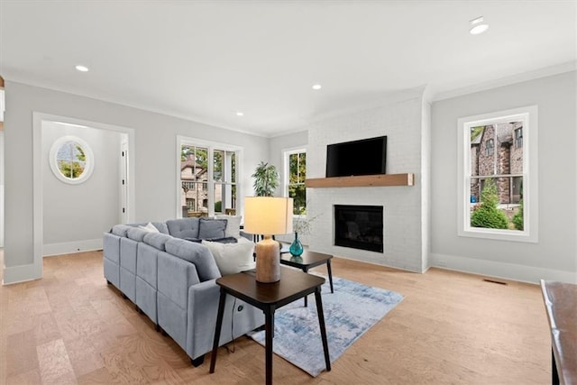 living room featuring a brick fireplace, light hardwood / wood-style floors, and ornamental molding