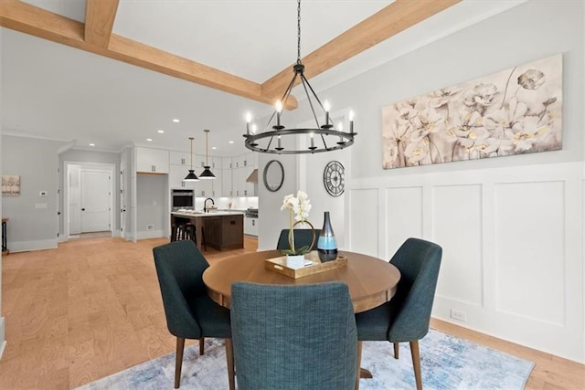 dining room featuring light wood-type flooring, sink, beam ceiling, and an inviting chandelier