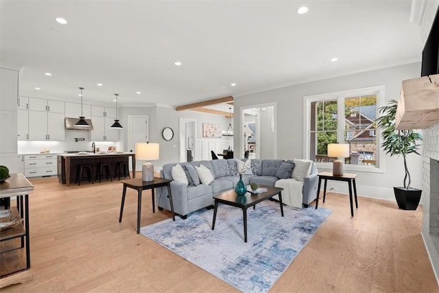 living room featuring crown molding, a brick fireplace, and light hardwood / wood-style flooring