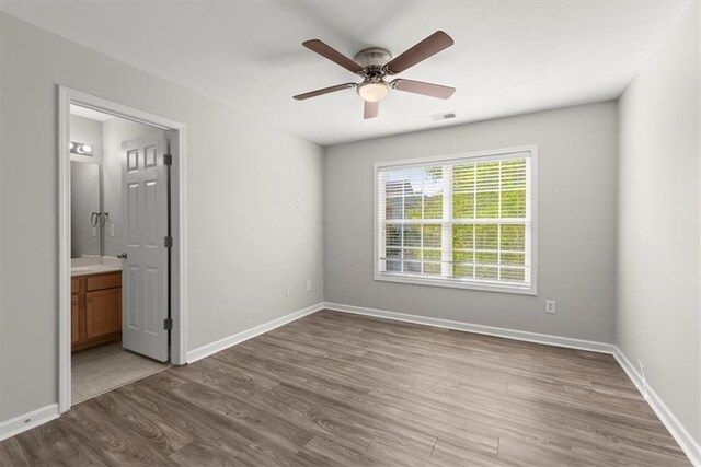 unfurnished bedroom featuring ceiling fan, hardwood / wood-style flooring, and ensuite bathroom