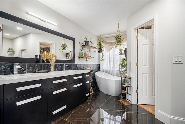 full bathroom featuring marble finish floor, double vanity, a soaking tub, and a sink