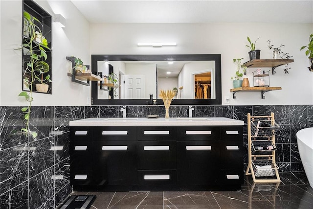 full bath featuring a soaking tub, marble finish floor, a sink, and double vanity