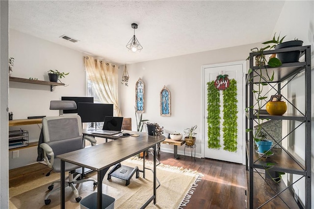 office space with baseboards, a textured ceiling, visible vents, and wood finished floors