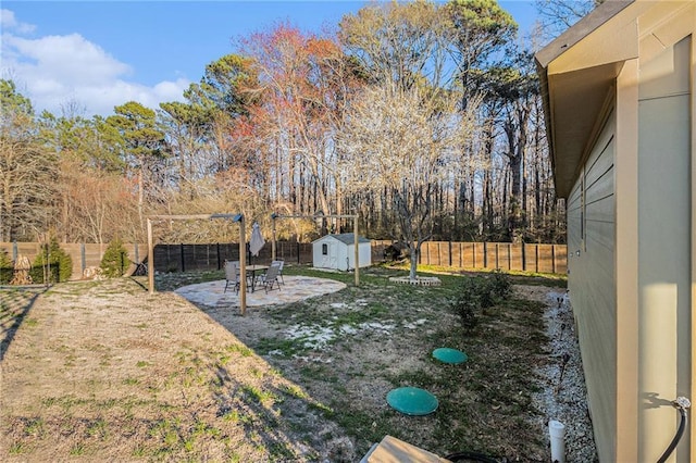 view of yard featuring an outbuilding, a fenced backyard, a patio, and a storage shed