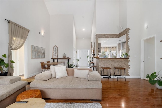 living room with a high ceiling, baseboards, and wood finished floors