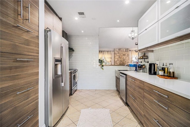 kitchen featuring light tile patterned floors, stainless steel appliances, visible vents, light countertops, and glass insert cabinets