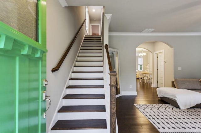 stairway featuring a notable chandelier, arched walkways, baseboards, wood finished floors, and ornamental molding
