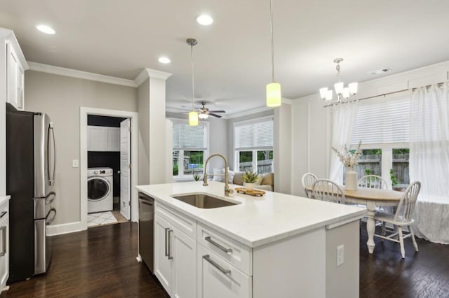 kitchen with appliances with stainless steel finishes, a sink, light countertops, washer / dryer, and white cabinetry