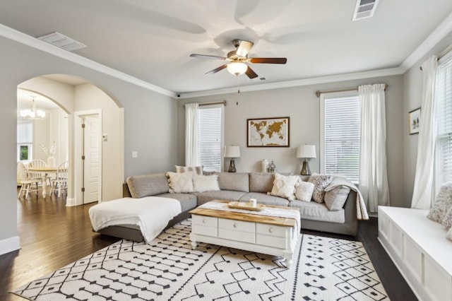 living area featuring arched walkways, ceiling fan with notable chandelier, wood finished floors, and visible vents