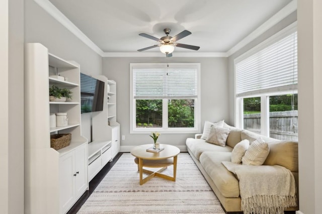 living area featuring crown molding, baseboards, a ceiling fan, and dark wood finished floors
