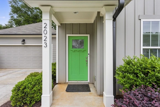 entrance to property with an attached garage, board and batten siding, and concrete driveway