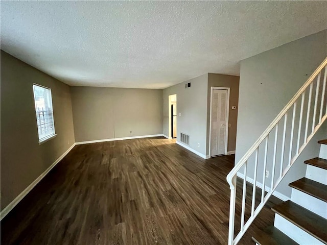 spare room featuring a textured ceiling and dark hardwood / wood-style flooring