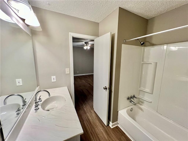 bathroom with  shower combination, a textured ceiling, hardwood / wood-style floors, ceiling fan, and vanity