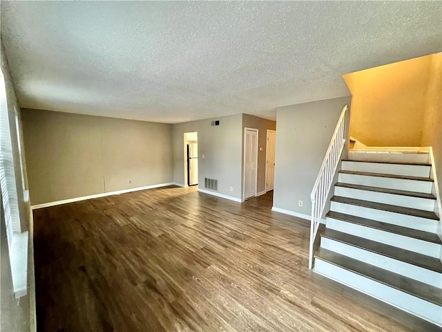 unfurnished living room featuring a textured ceiling and wood-type flooring