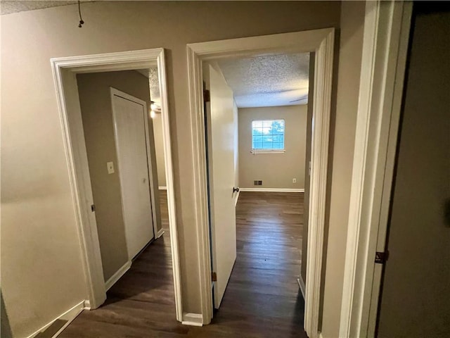 corridor featuring a textured ceiling and dark hardwood / wood-style floors