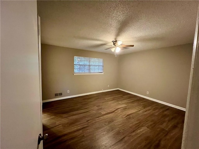 spare room with dark wood-type flooring, ceiling fan, and a textured ceiling