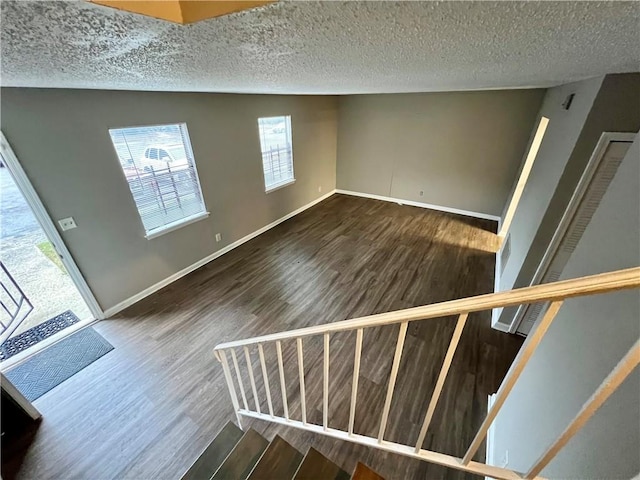 interior space with a textured ceiling and dark hardwood / wood-style floors