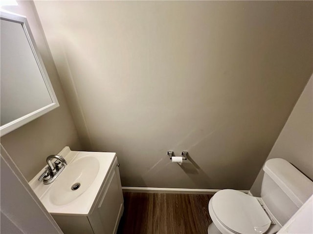 bathroom with toilet, vanity, and wood-type flooring