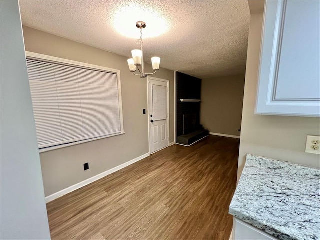 unfurnished dining area with a large fireplace, a textured ceiling, and hardwood / wood-style floors