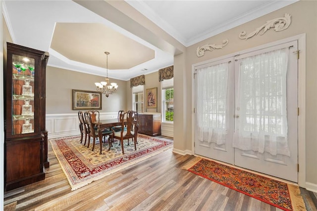 3633 Gilpin Ct, Lawrenceville, GA 30044 - dining space featuring wood finished floors, a chandelier, a raised ceiling, crown molding, and a wainscoted wall