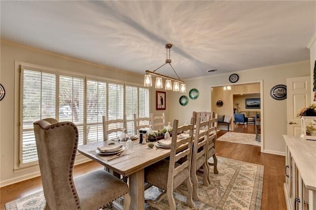 dining space with baseboards, ornamental molding, and dark wood-type flooring