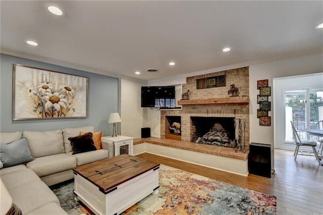 living area with a brick fireplace, crown molding, hardwood / wood-style floors, and recessed lighting