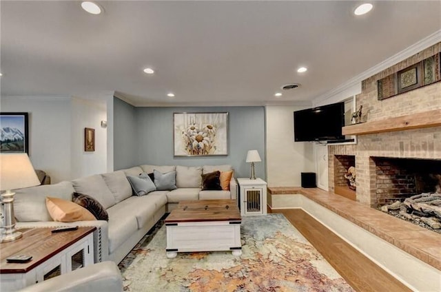 living room with recessed lighting, a brick fireplace, crown molding, and wood finished floors