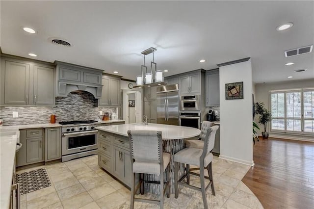 kitchen with visible vents, decorative backsplash, premium appliances, and gray cabinetry