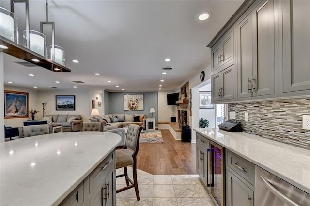 kitchen with tasteful backsplash, a fireplace with raised hearth, wine cooler, gray cabinetry, and recessed lighting