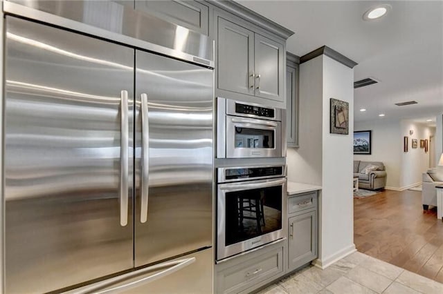 kitchen featuring open floor plan, stainless steel appliances, visible vents, and gray cabinetry