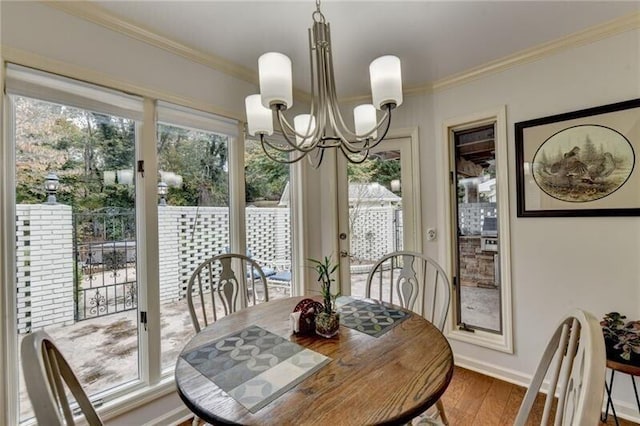 dining area with wood finished floors, crown molding, baseboards, and an inviting chandelier