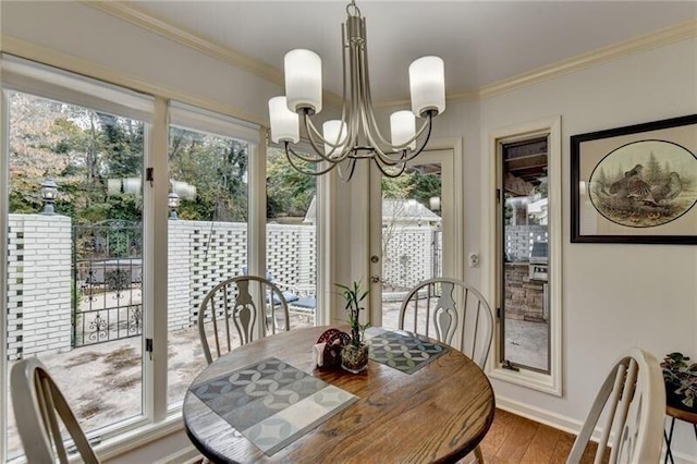 dining area with ornamental molding, wood finished floors, baseboards, and an inviting chandelier