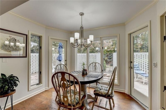 dining room with a chandelier, ornamental molding, light wood-style flooring, and baseboards