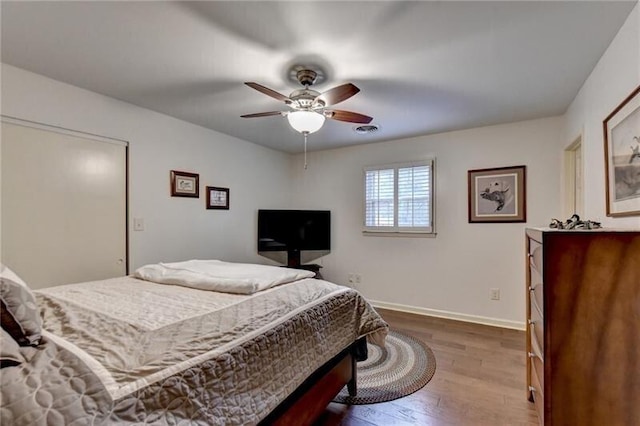 bedroom featuring a ceiling fan, baseboards, visible vents, and wood finished floors