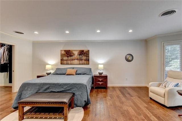 bedroom featuring baseboards, visible vents, wood finished floors, and ornamental molding