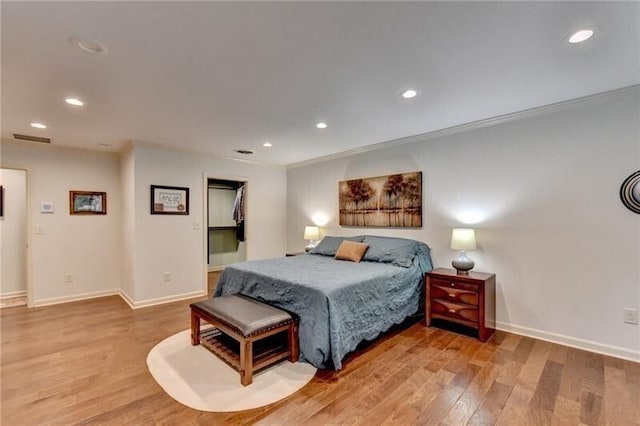 bedroom featuring baseboards, crown molding, wood finished floors, and recessed lighting