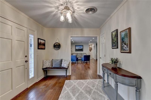 foyer featuring baseboards, wood-type flooring, visible vents, and crown molding