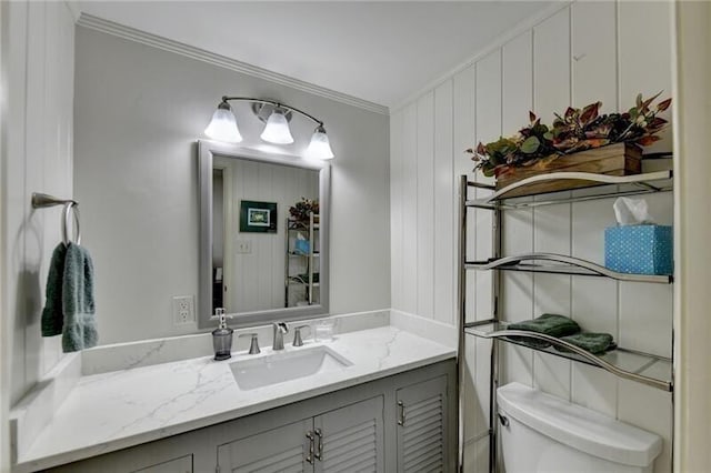 bathroom featuring toilet, ornamental molding, and vanity