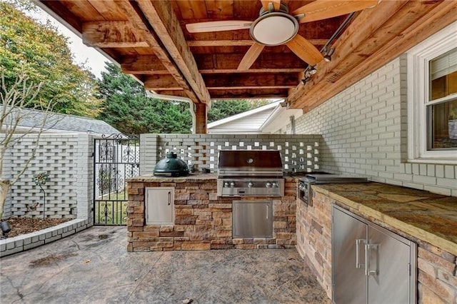 view of patio featuring exterior kitchen, a gate, a grill, and fence