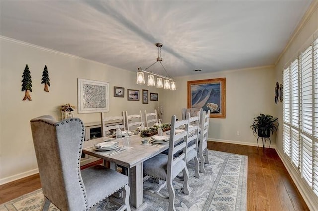 dining space with wood-type flooring, ornamental molding, and baseboards