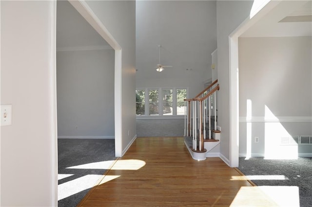 hallway featuring baseboards, wood finished floors, and stairs