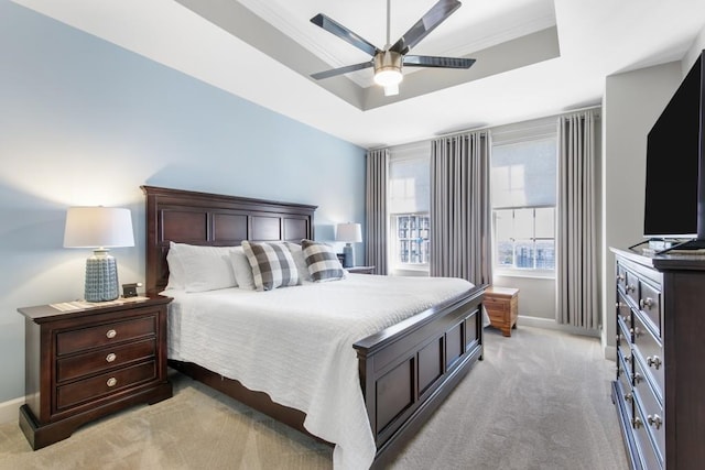 carpeted bedroom featuring crown molding, ceiling fan, and a raised ceiling