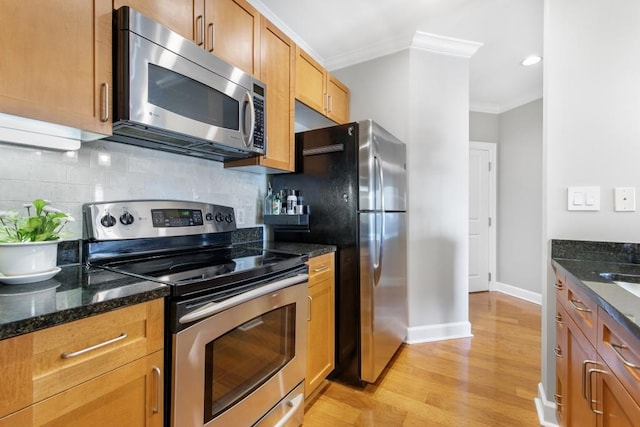 kitchen with backsplash, dark stone counters, ornamental molding, stainless steel appliances, and light hardwood / wood-style flooring